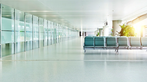 Vestíbulo de aeropuerto moderno y luminoso, con una fila de asientos junto a los ventanales
