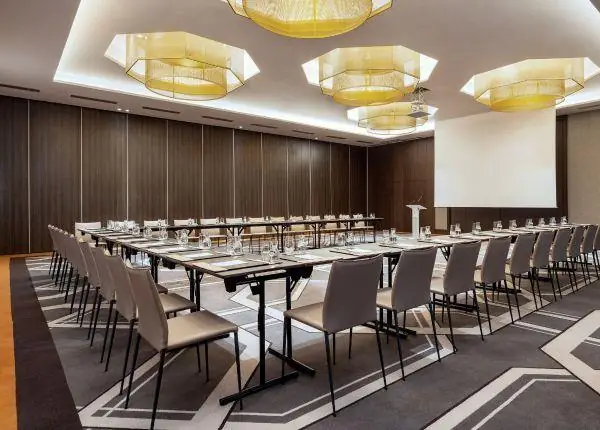 Sala de seminarios con mesas en U, lámparas doradas y paneles de madera, Rabat