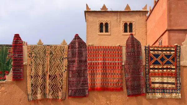 Alfombras bereberes colgadas ante una kasbah de tapial